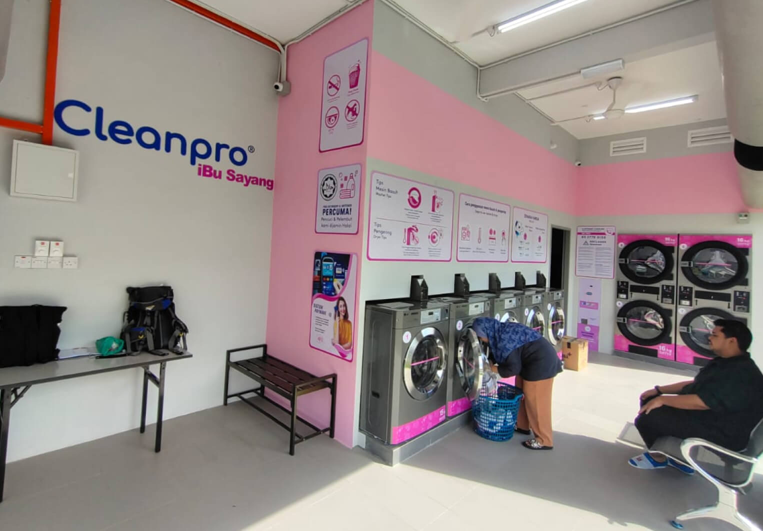 Cleanpro Ibu Sayang Tawau customers inserting their laundry into the washing machines